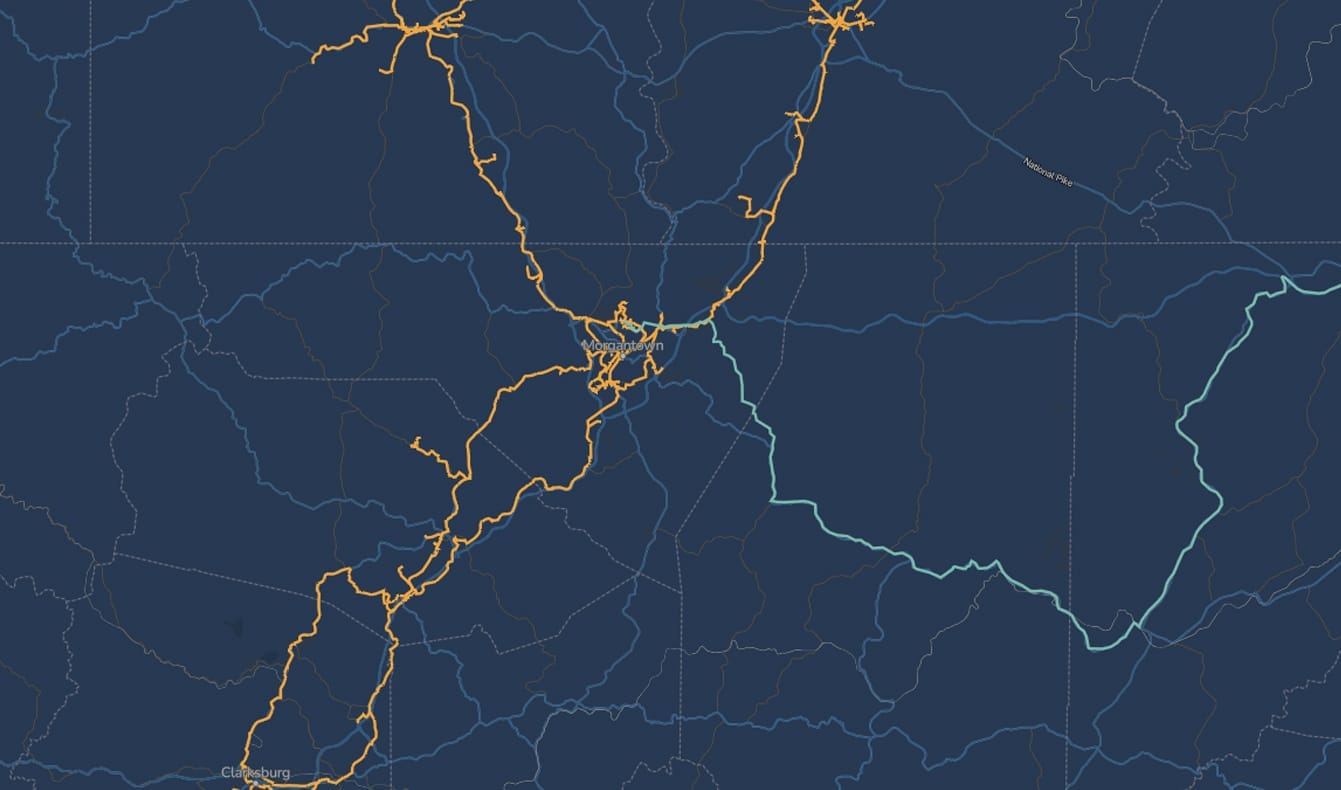 A dark blue map with various orange and light blue lines showing roadways and borders. The lines converge and intersect near the center, indicating a hub or city surrounded by a network of routes. No text labels are visible.