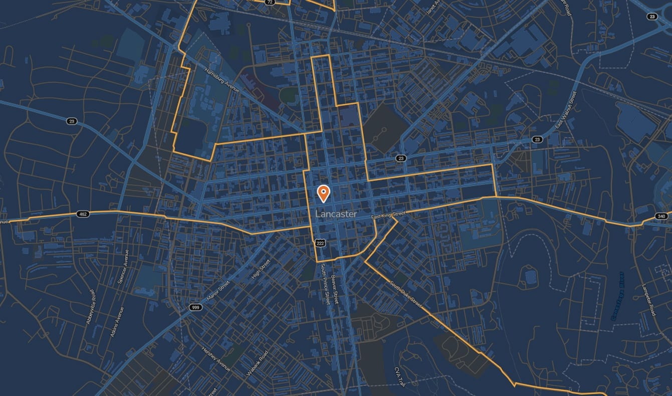 A digital map highlighting central Lancaster with orange borders; a red location pin marks the city center. Streets and major routes are visible on a dark blue background.